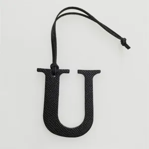 Black leather letter U charm detail, elegant handbag pendant initial accessory close-up