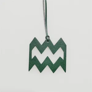 Close-up detail of the green leather Aquarius zodiac symbol pendant with matching leather cord.