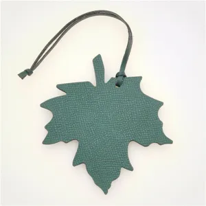 Green leather maple leaf bag charm, stylish car pendant accessory with black strap.