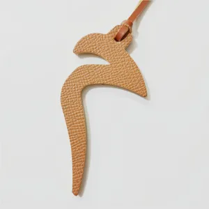 Detailed view of brown textured leather Arabic alphabet bag charm accessory, close-up texture shot.