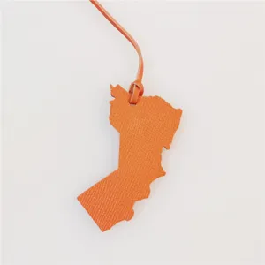 Oman map shape leather bag charm in orange, elegant handbag pendant accessory detail shot.
