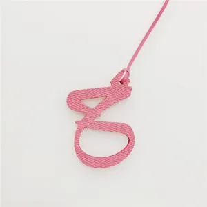 Ciondolo con lettera araba in pelle rosa variante, ideale per borse e decorazioni auto.