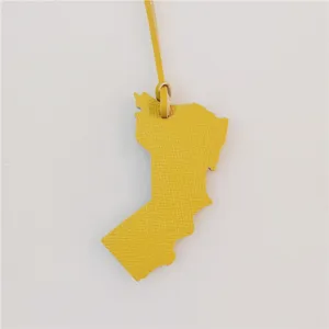Detailed close-up view of the yellow leather map shape bag charm hanging on a string.