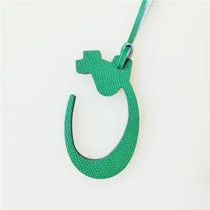 Green leather Arabic letter bag charm detail showcasing textured surface and edge paint finish.