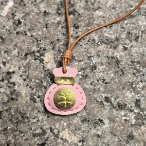 Handmade genuine leather lucky bag pendant detail shot, pink leather charm for bags and keys.