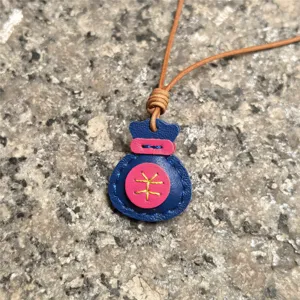 Handcrafted genuine leather lucky bag pendant detail shot, stylish leather keychain accessory.