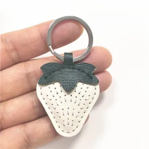 Detailed view of the cute leather strawberry keychain charm with white body and green leaf.