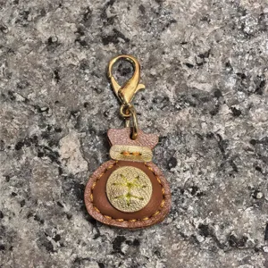Llavero con dije de bolsa de la suerte de cuero genuino hecho a mano con cierre metálico.