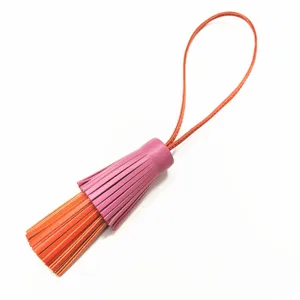 Detailansicht eines eleganten zweifarbigen Lederquasten-Taschenanhängers mit langem Riemen.