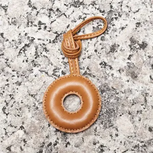 Light brown leather ring bag charm, delicate handcrafted stitch detail, elegant accessory loop.