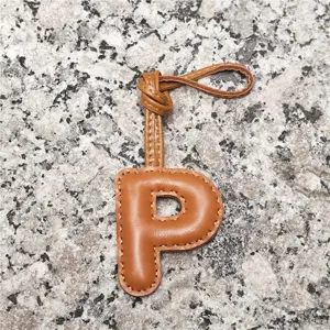 Close-up of light brown leather letter P bag charm showing neat stitching and loop strap.