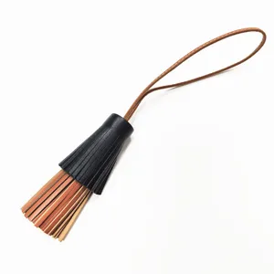 Detailansicht des zweifarbigen Leder Quasten Taschenanhängers mit Riemen für elegante Handtaschen.