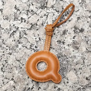 Close-up detail of the stylish brown leather letter Q bag charm and pendant accessory.
