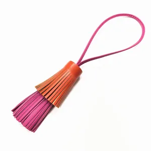 Detaillierte Nahaufnahme des zweifarbigen Leder-Quasten-Taschenanhängers mit Rosaschlaufe.