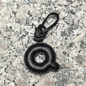 Detailed close-up of a black leather letter Q bag charm pendant showcasing fine texture.