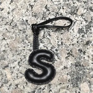 Black leather letter S charm pendant, stylish alphabet initial bag accessory for women.