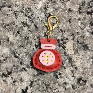 Primer plano detallado del amuleto llavero de la bolsa de la suerte de cuero rojo oro.