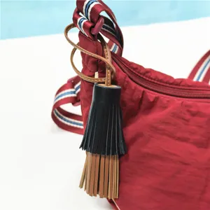 Elegante rote Nylon-Umhängetasche mit stilvollem schwarz-braunen Leder-Quastenanhänger.