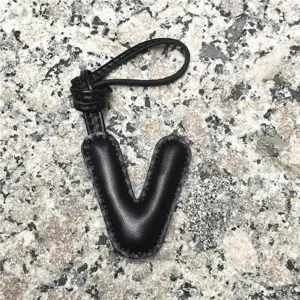 Black leather letter V bag charm and initial keychain for women, stylish car accessory detail view.