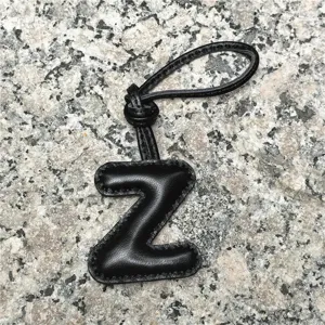 Close-up detail of the black leather letter Z bag charm pendant showing fine stitching texture on stone.