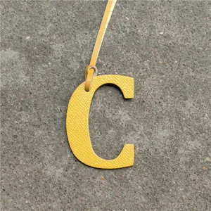 Yellow leather letter C bag charm detail showcasing fine leather texture and hanging strap.