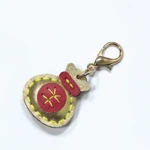 Llavero de bolsa de la suerte de cuero hecho a mano, detalle dorado y rojo para bolsas.
