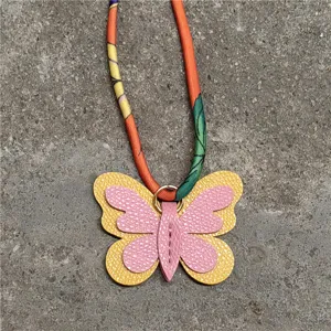 Vista detallada del colgante de bolso mariposa de minicuero con cinta de seda de colores.