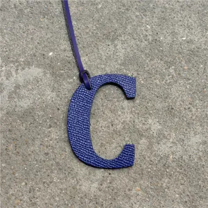 Blue leather letter C bag charm detail close-up view, stylish alphabet accessory for purse.