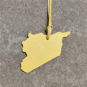 Detailed close-up of the yellow leather map bag charm, showing fine texture and strap detail.