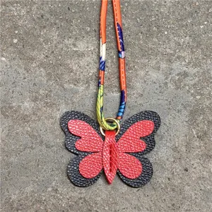 Detalle de primer plano del dije de bolso de mariposa de cuero con correa de pañuelo de seda.