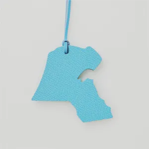 Gros plan sur le pendentif carte du Koweït en cuir bleu pour sac et décoration de voiture.