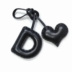 Black leather letter D and heart bag charm detail close-up view showing exquisite stitching
