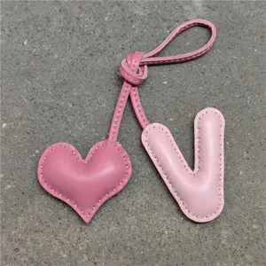 Colgante de bolso de cuero rosa con corazón y letra V, llavero artesanal elegante para mujeres.