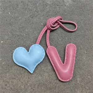 Colgante de bolso de cuero hecho a mano con corazón azul y letra V rosa detalles.