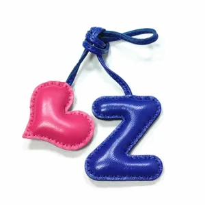 Leather letter Z and heart bag charm detail showing handmade stitching and vibrant blue and pink.