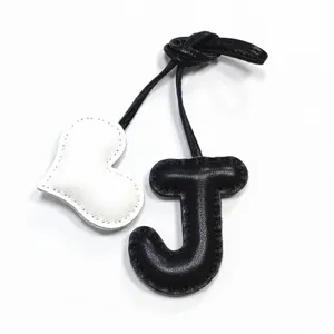 Ciondolo borsa artigianale in pelle lettera J e cuore, elegante design in bianco e nero.