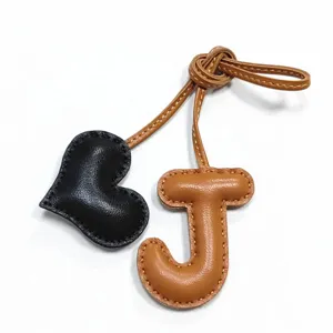 Ciondolo per borsa artigianale in pelle con lettera J e cuore, elegante accessorio alla moda.