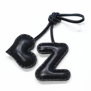 Black leather letter Z and heart bag charm close-up, handmade aesthetic accessory pendant.