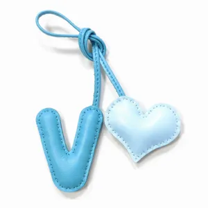 Primer plano detalle de letra V de cuero azul claro y corazón, colgante de bolso hecho a mano.