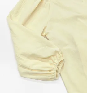 Detailaufnahme des hellgelben Kleides mit Puffärmel, strukturierter Stoff und elastisches Bündchen.