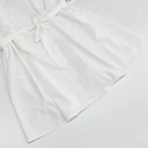 Close-up detail of white satin loungewear robe showing soft fabric texture and waist belt.
