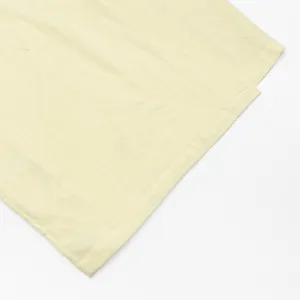 Hellgelbes Stoffdetail, das die weiche Textur und feine Nähte des Kleides zeigt.