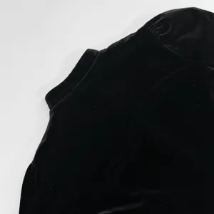 Κοντινή λεπτομέρεια του μαύρου βελούδινου τοπ με κοντά μανίκια, κομψός σχεδιασμός.