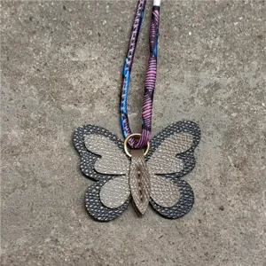 Vista detallada del lindo colgante de bolso de mariposa de cuero con cinta colorida.