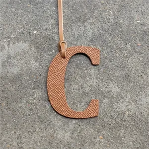 Leather letter C bag charm detail shot, textured brown leather pendant accessory display.