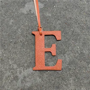 Orange leather letter E bag charm detail view, stylish handbag pendant accessory.