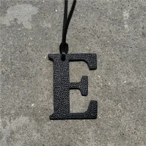 Black leather letter E bag charm detail, luxury style pendant with strap for handbags.