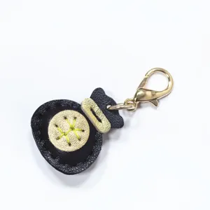 Llavero de bolsa de la suerte de cuero hecho a mano, vista detallada en negro y oro.
