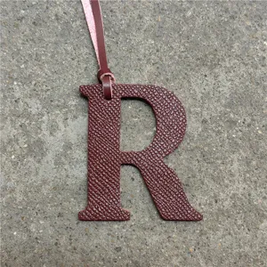 Leather letter R bag charm detail shot, stylish initial handbag pendant with hanging strap.