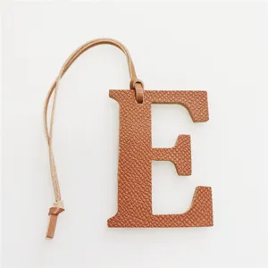 Leather capital letter E bag charm detail, stylish orange purse accessory with leather strap.